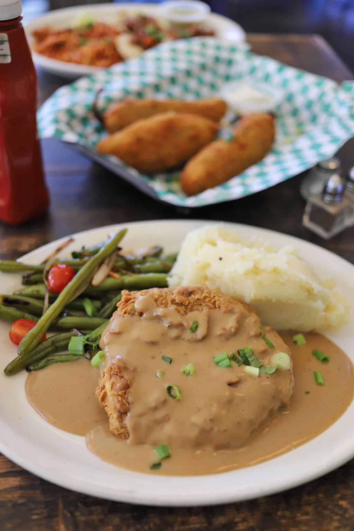 Chicken fried seitan on plate with mashed potatoes and green beans.