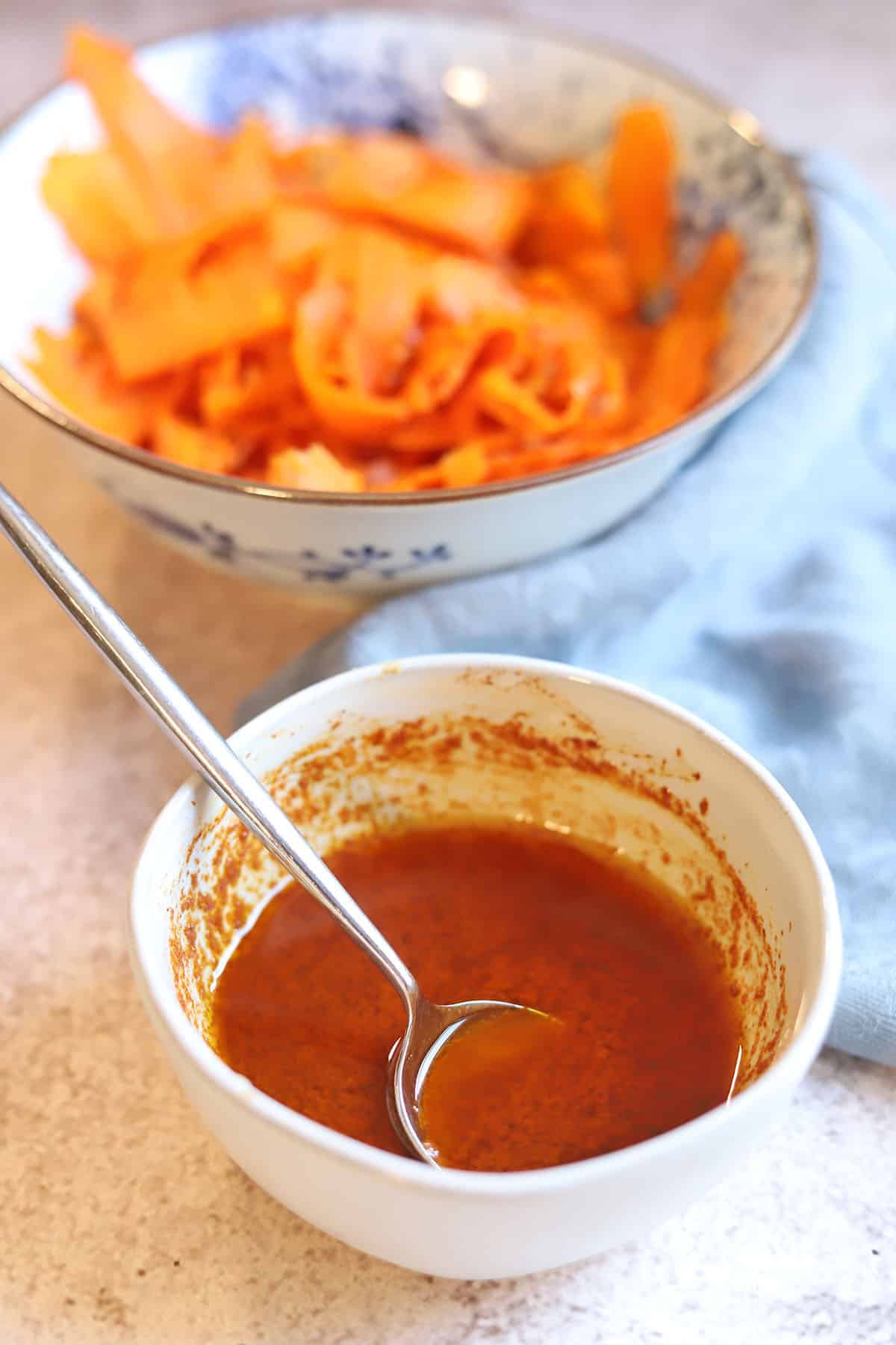 Marinade for carrot lox by shredded carrot ribbons in bowl.