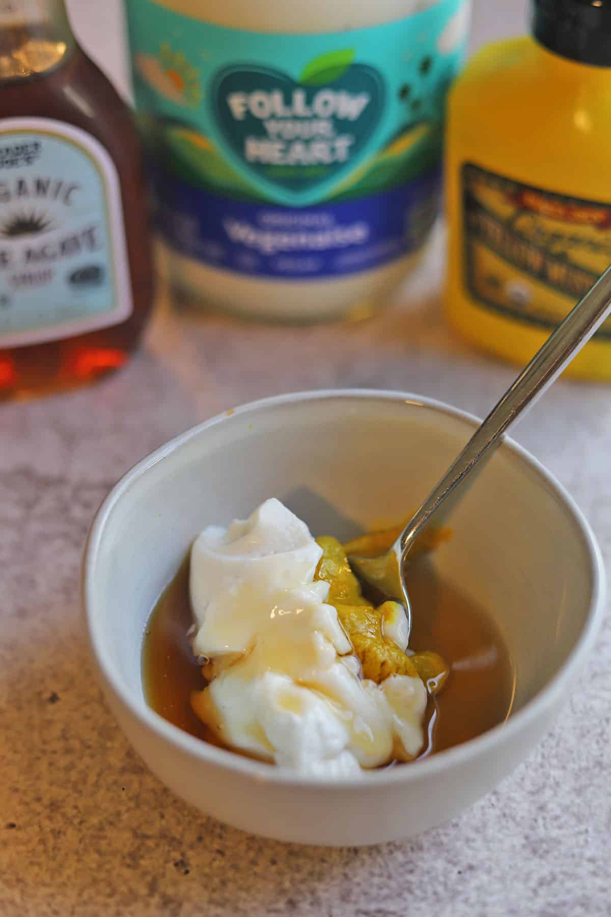 Vegan mayo, mustard, and agave nectar in bowl with spoon.