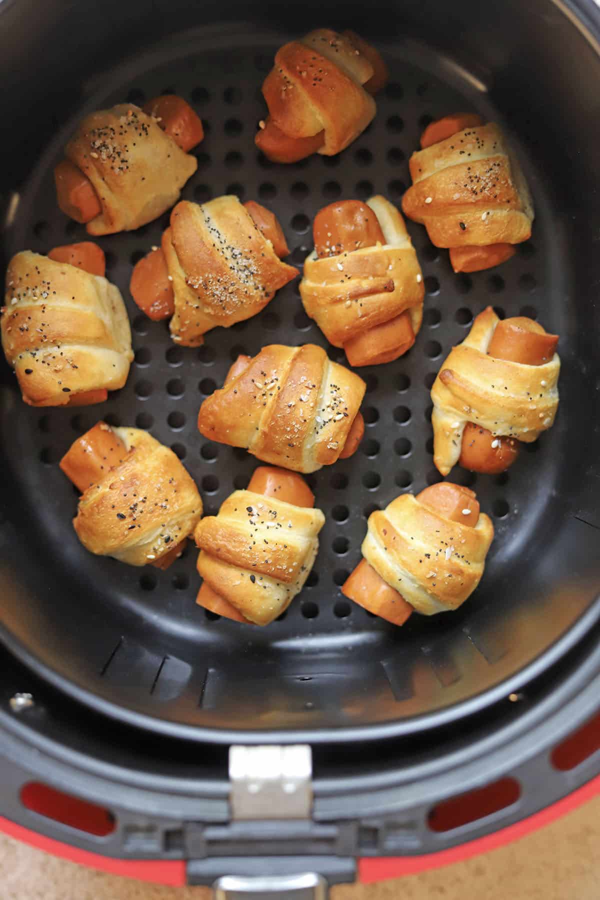 Crescent dough wrapped hot dogs in air fryer basket.
