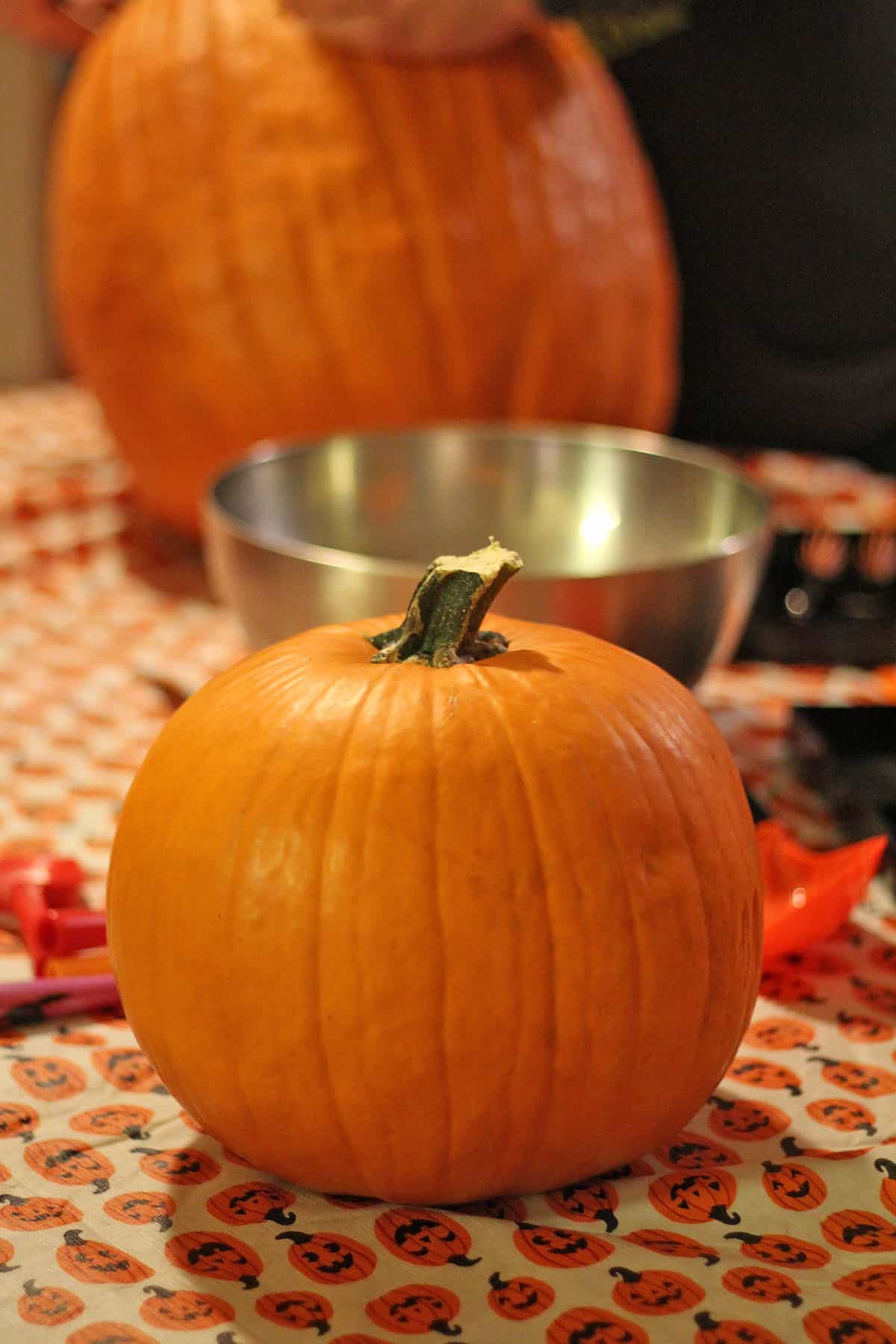 Pumpkin on table by metal bowl.