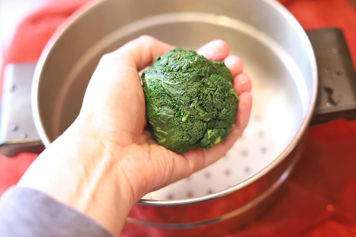 Ball of steamed kale in hand.