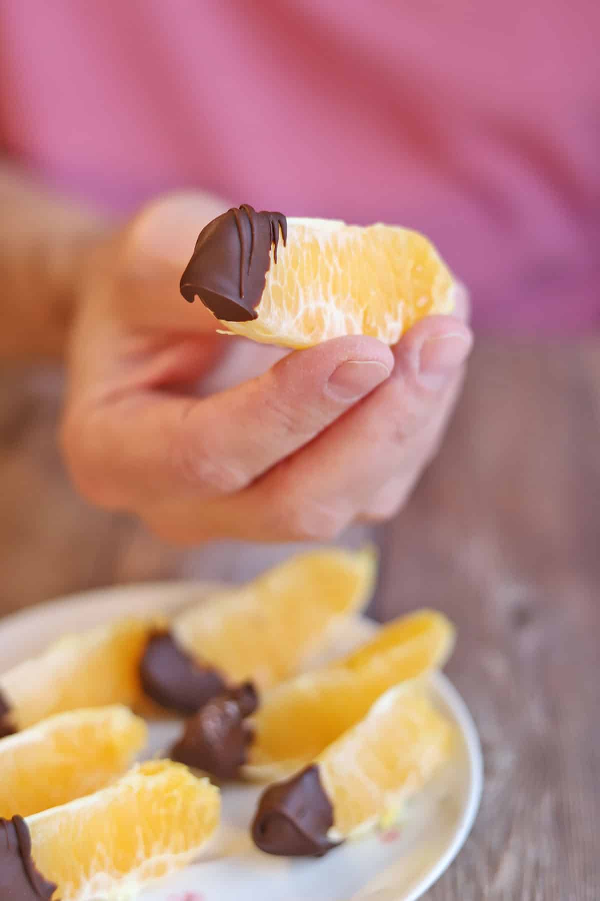 Hand holding a chocolate covered orange slice.