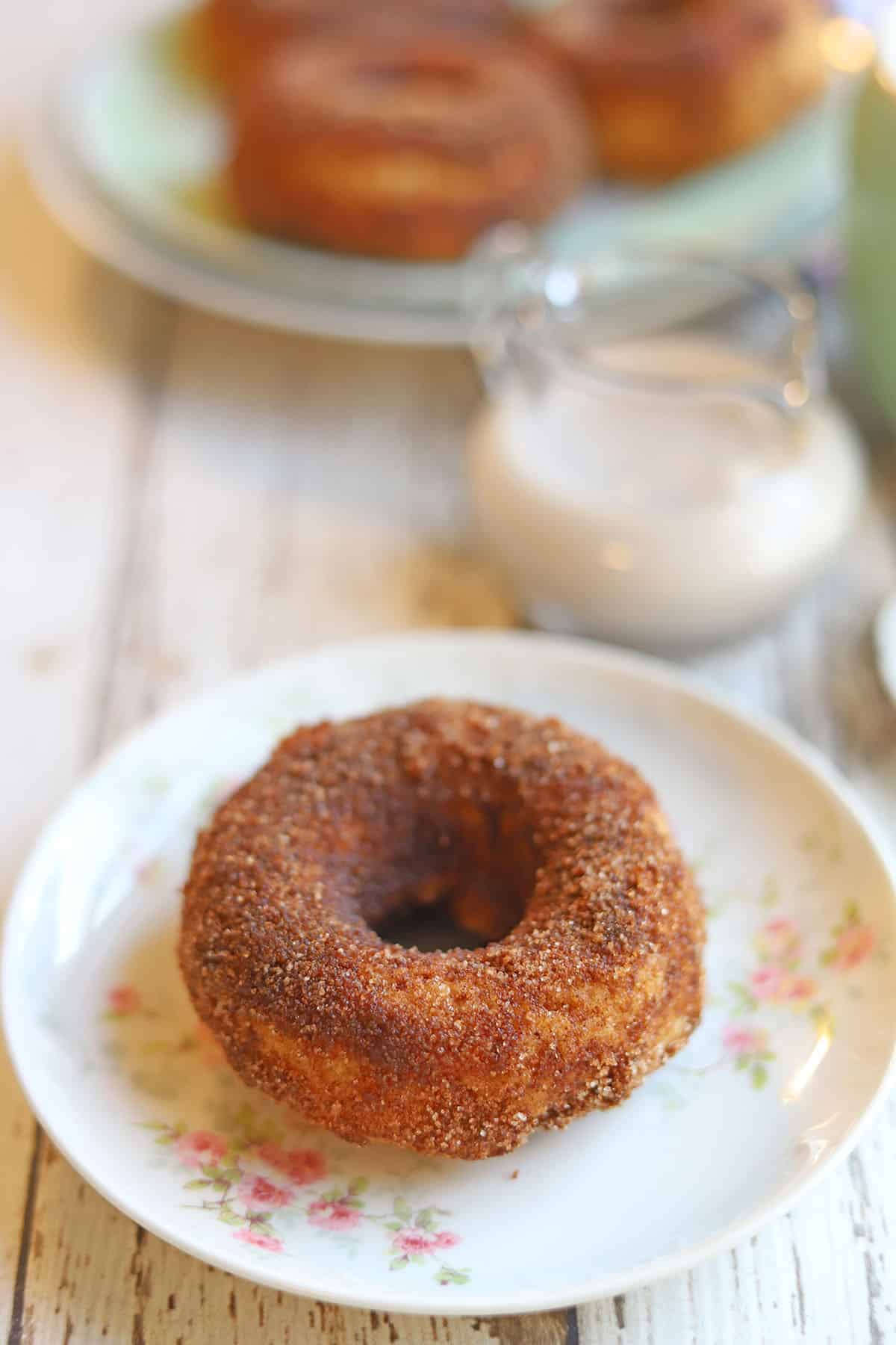 Cinnamon donut on floral plate.