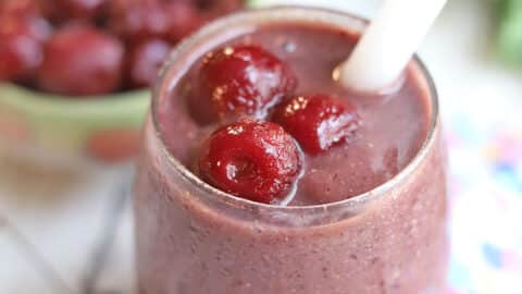 Close-up cherry smoothie, garnished with frozen cherries.