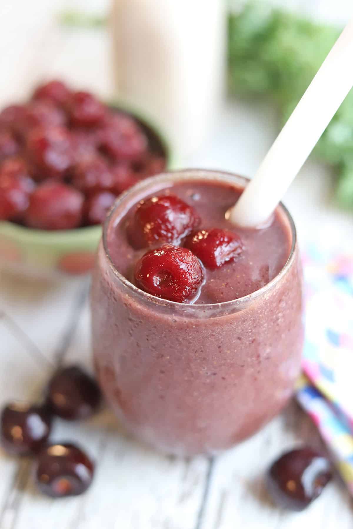 Close-up cherry smoothie, garnished with frozen cherries.