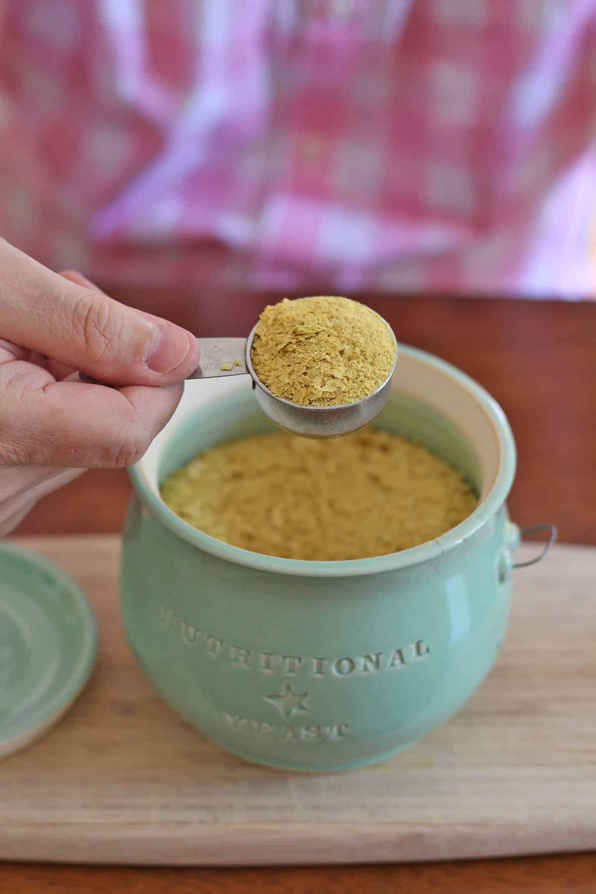 Measuring cup of nutritional yeast over jar.