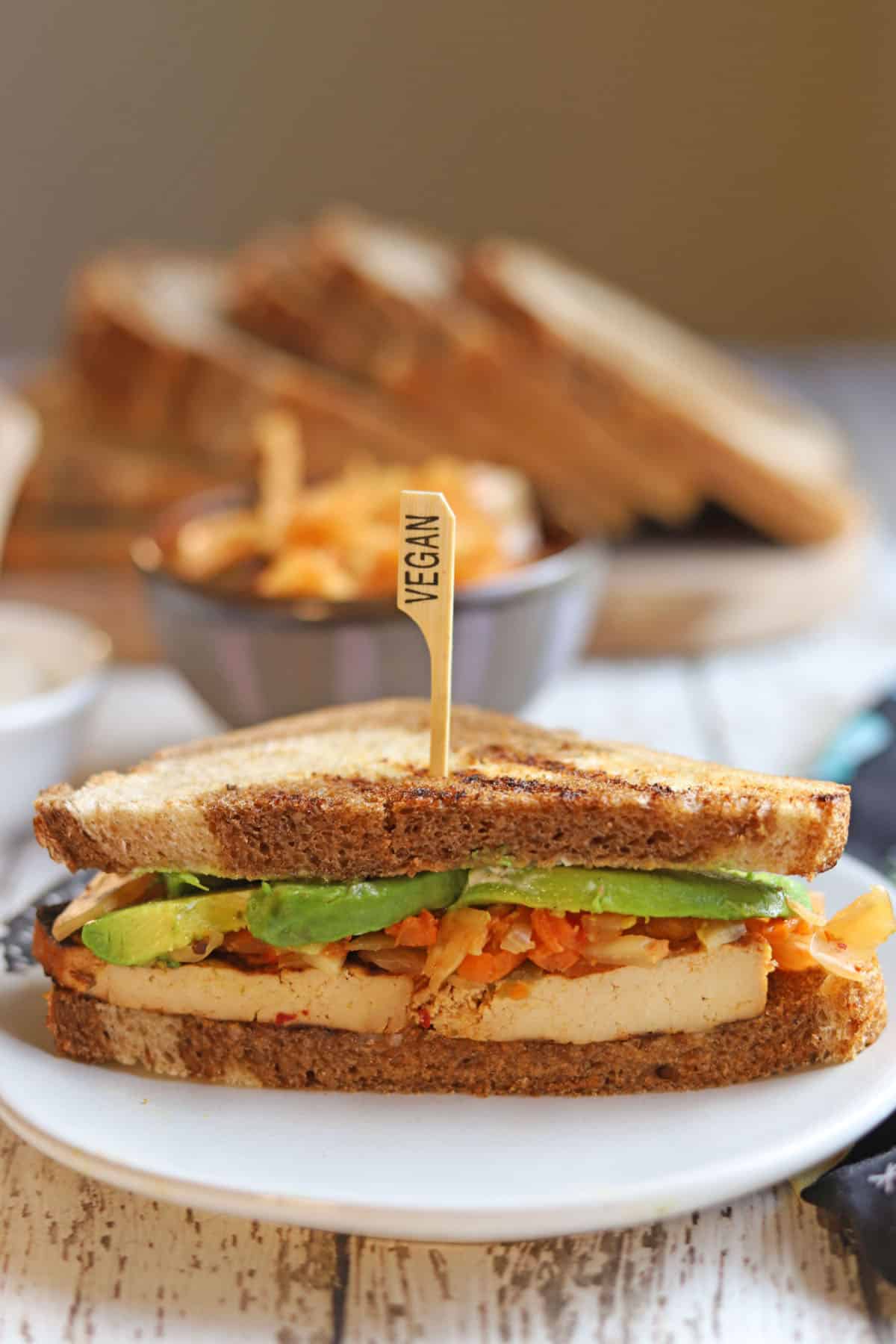 Bulgogi tofu sandwich cut in half, showing avocado and kimchi.