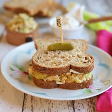 Vegan chickpea tuna salad on bread with pickle garnish.