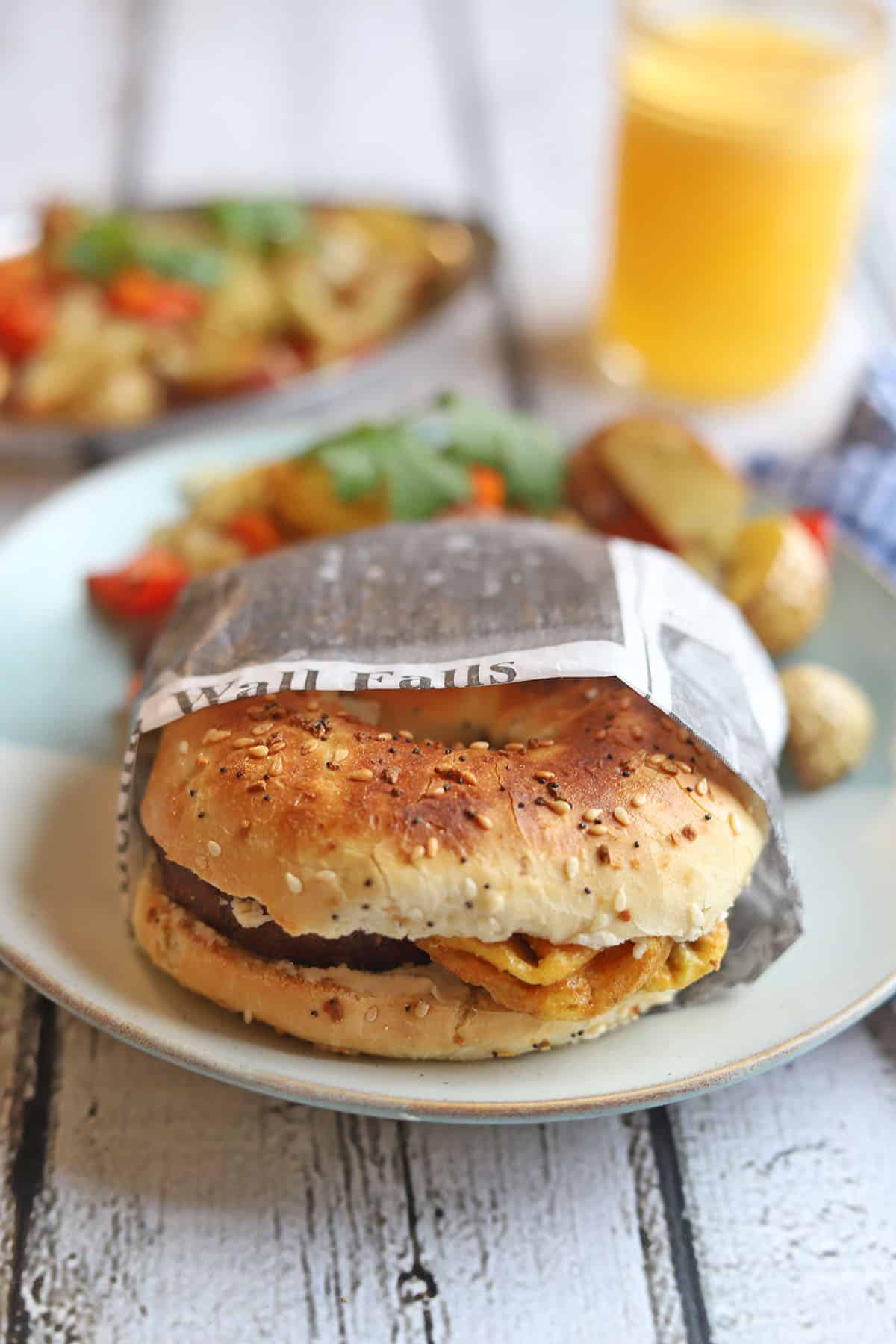 Vegan bagel breakfast sandwich wrapped in newspaper.