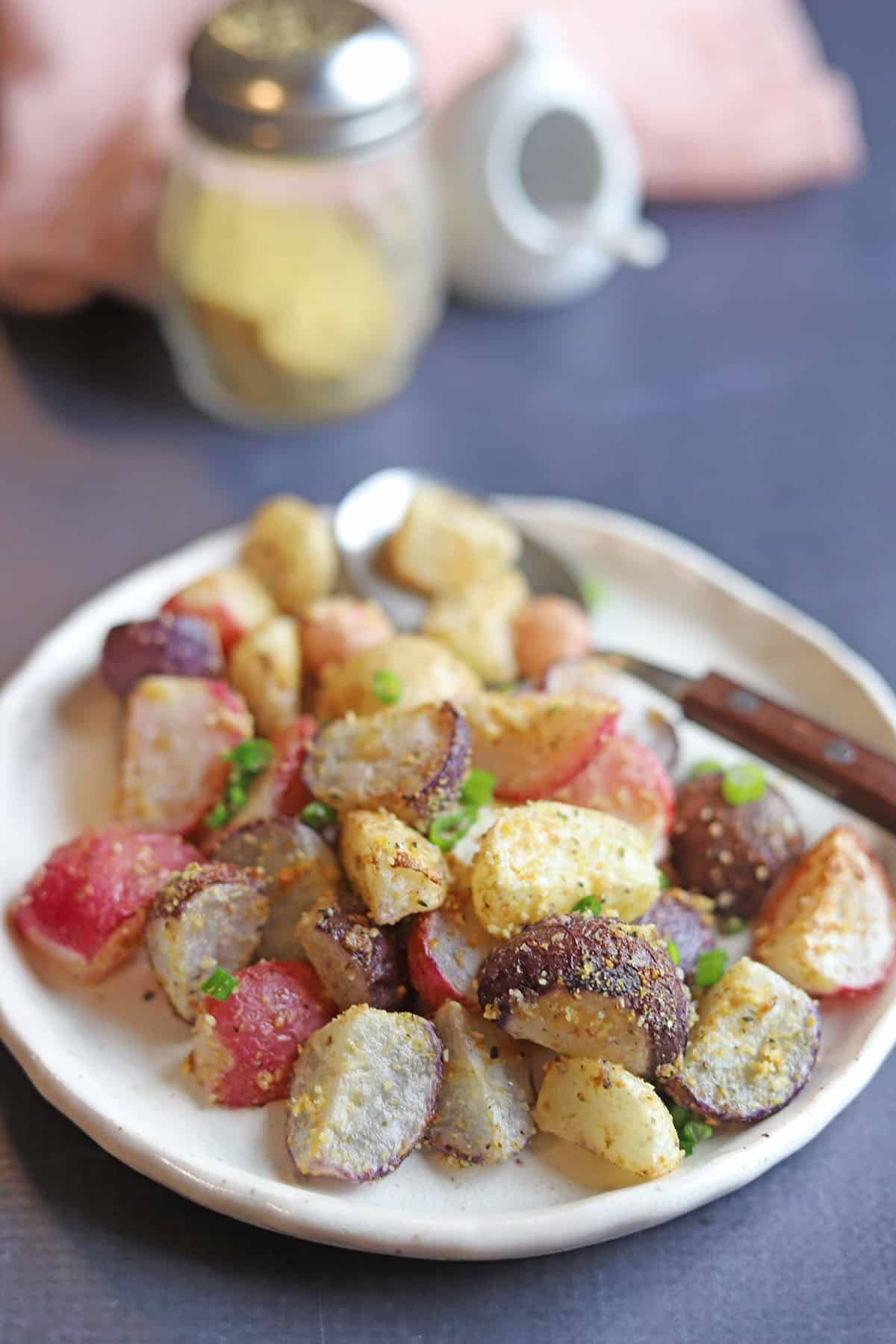 Roasted radishes on plate by cashew parmesan and salt.