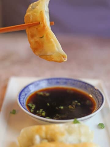 Gyoza hovering over dipping sauce.
