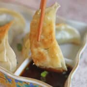 Text overlay: Easy gyoza dipping sauce. Dumpling being dipped into sauce with chopsticks.