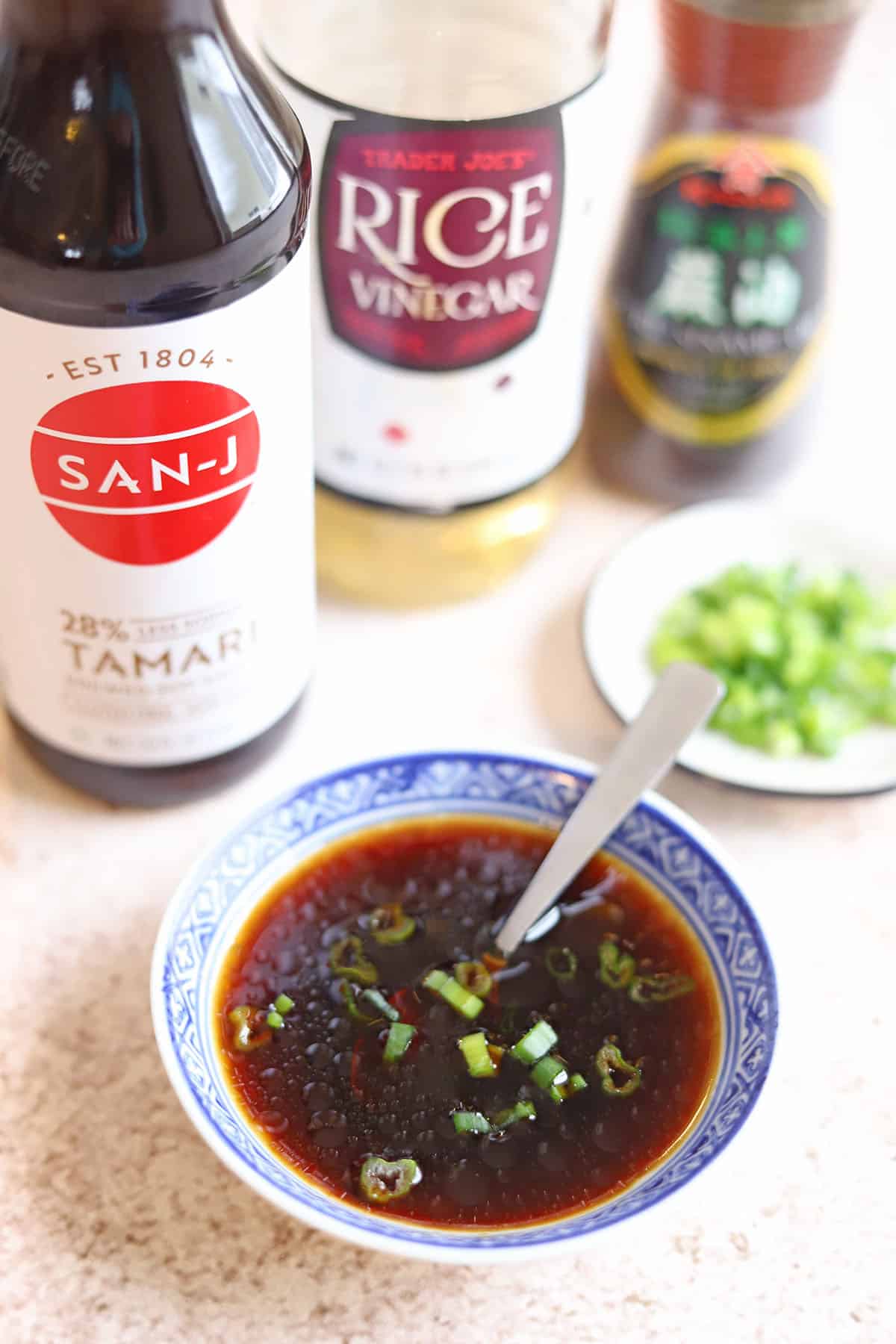 Tamari, rice vinegar, sesame oil, and scallions by gyoza dipping sauce in bowl.