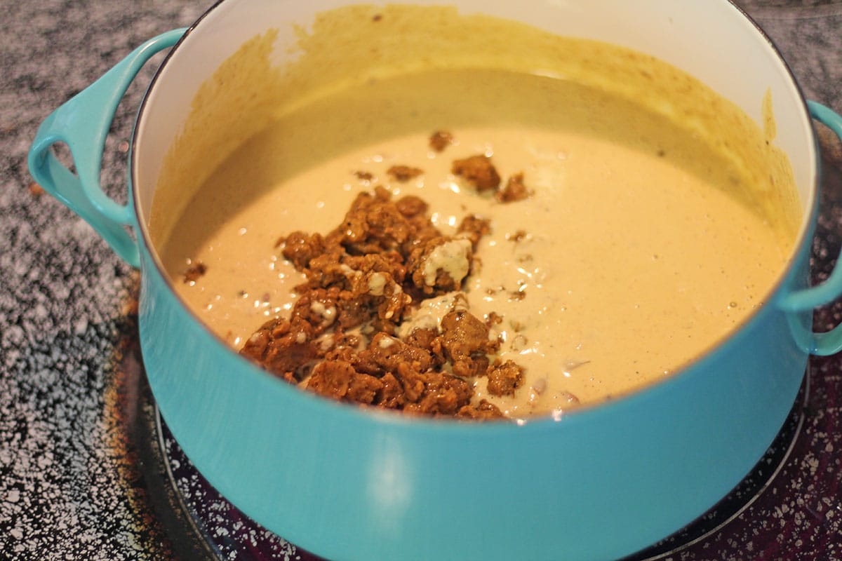 Add vegan chorizo to dairy free cheese sauce in pot.