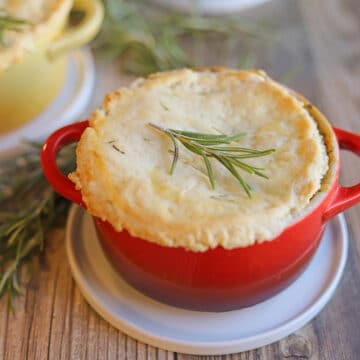 Miniature pot pie on white plate with rosemary garnish.