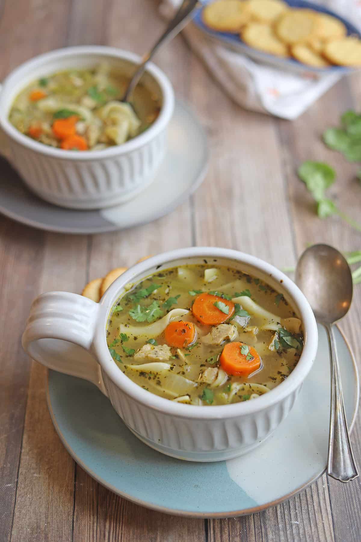 Vegetarian chicken noodle soup in bowls by crackers.