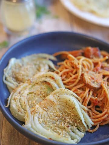 Three slices of roasted fennel by pasta with red sauce.