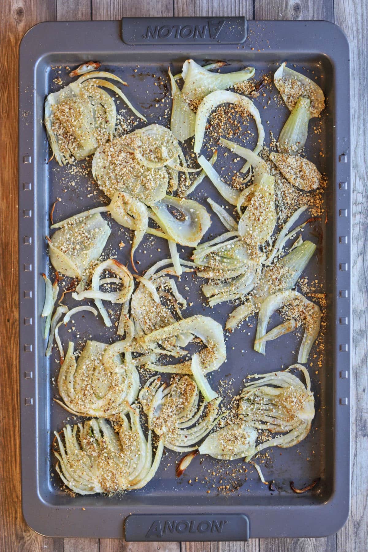 Fennel covered in vegan parmesan cheese on baking sheet.