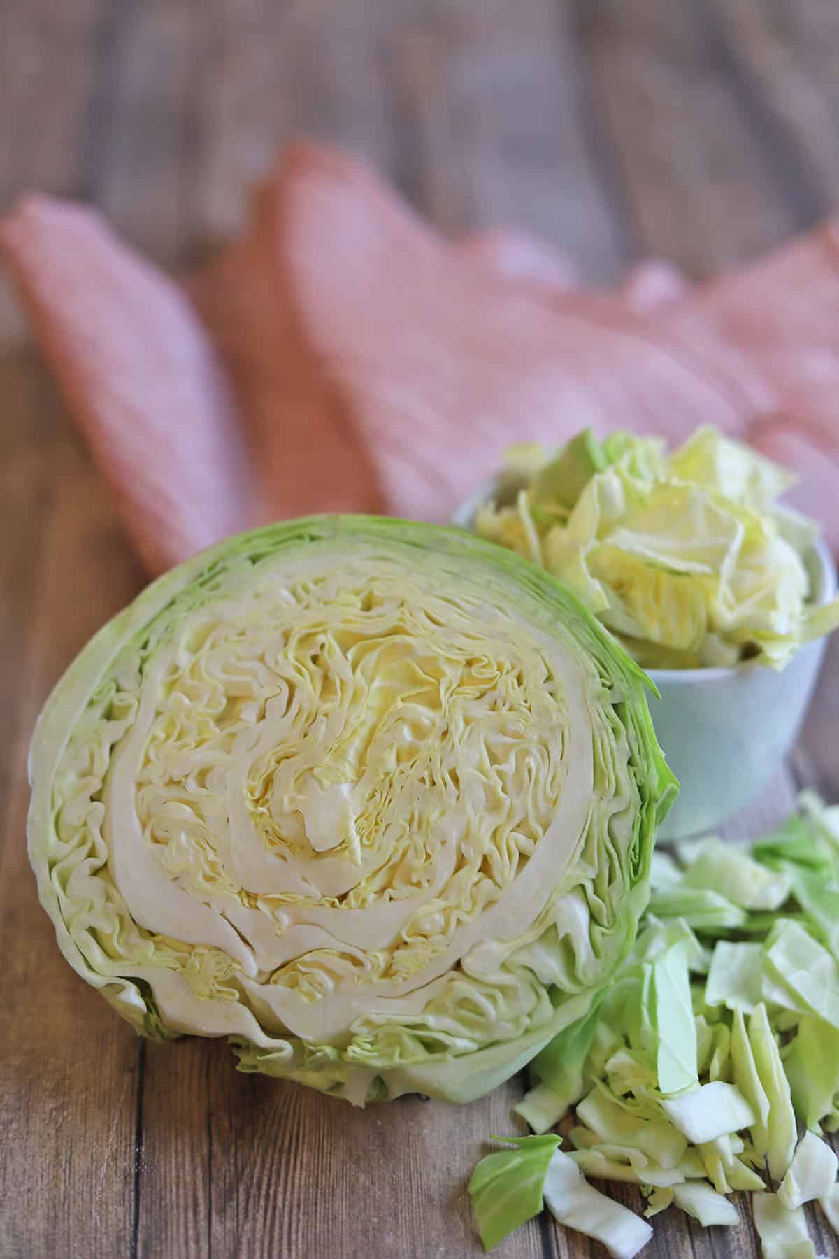 Cabbage head cut in half by chopped cabbage pieces.