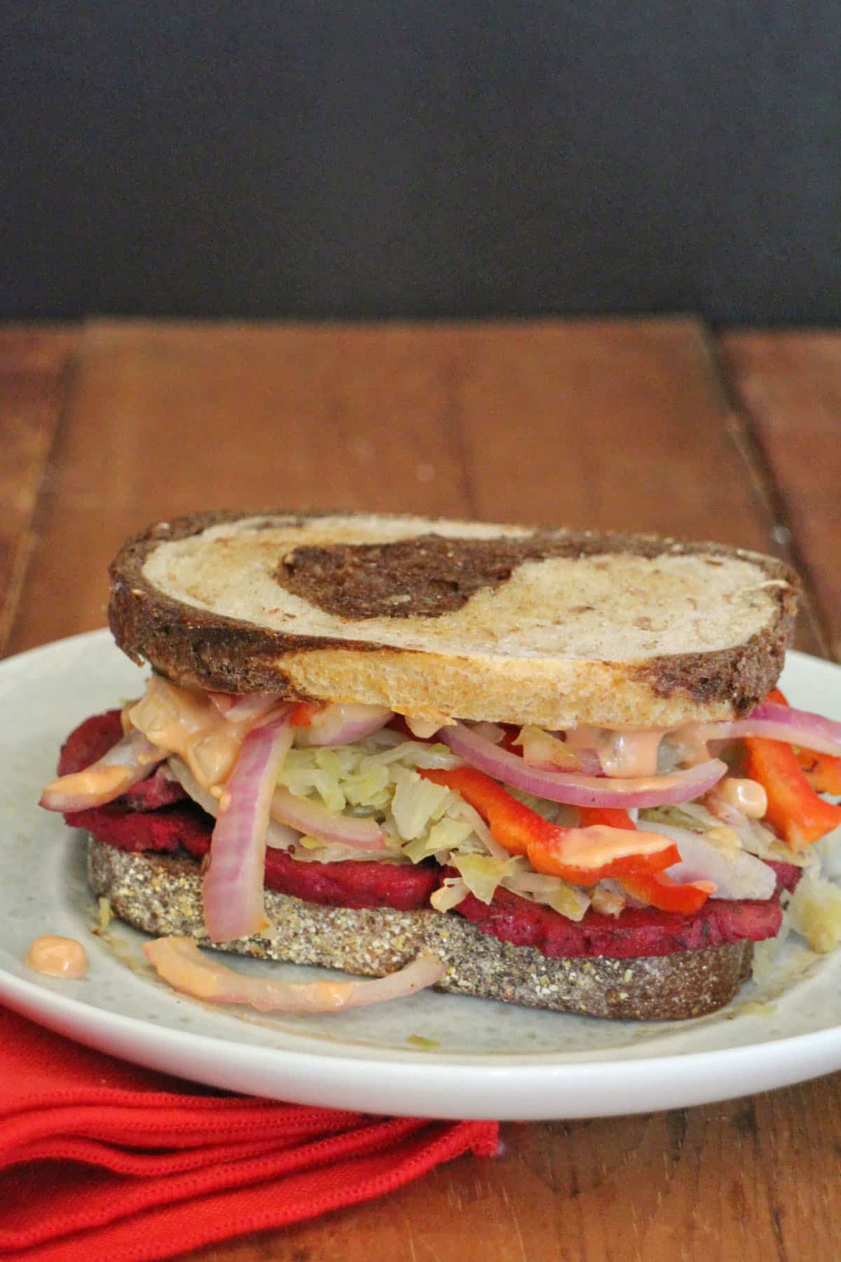 Vegan reuben sandwich on marbled rye with sauerkraut, peppers, and onions.