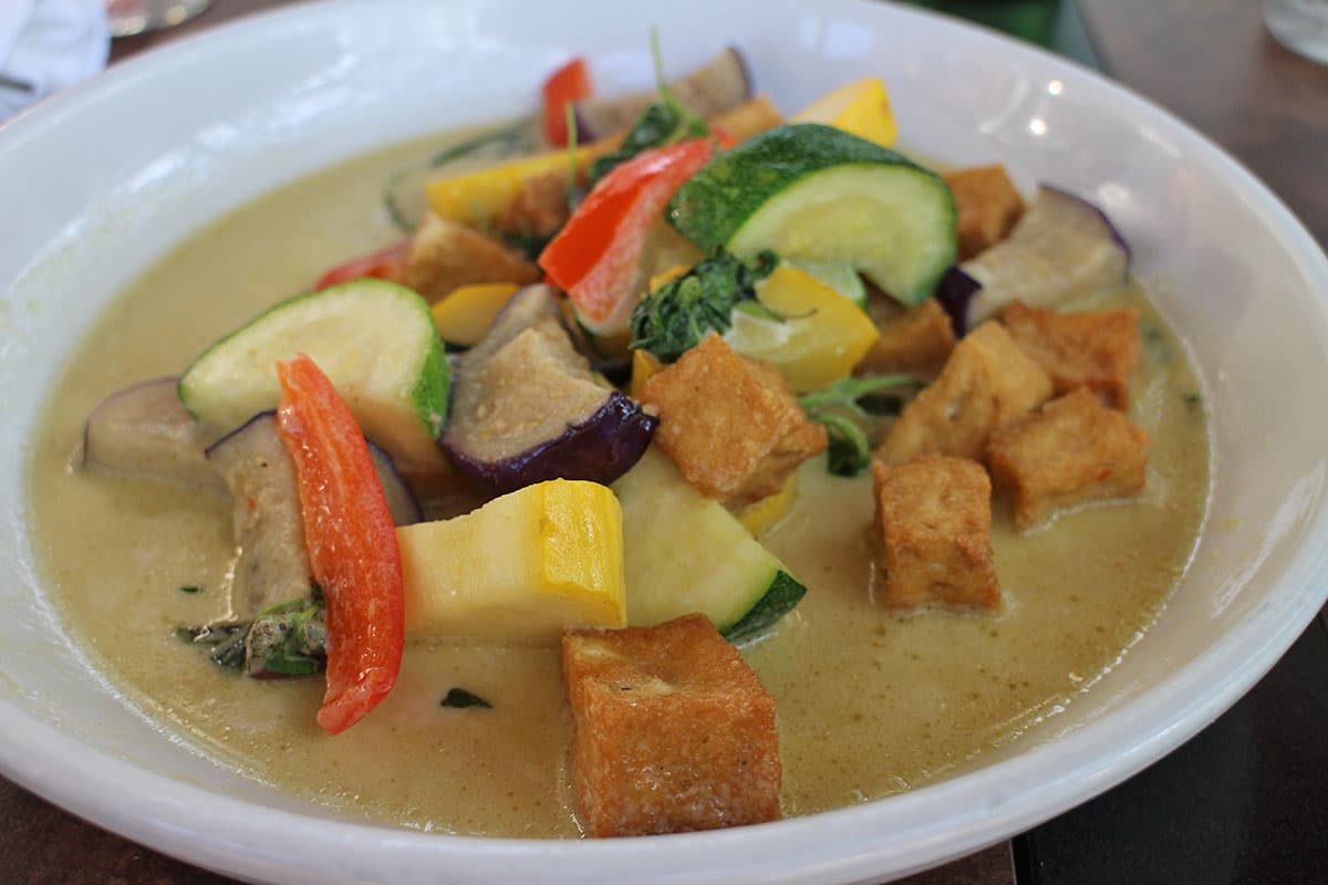 Coconut curry with large chunks of vegetables in bowl.