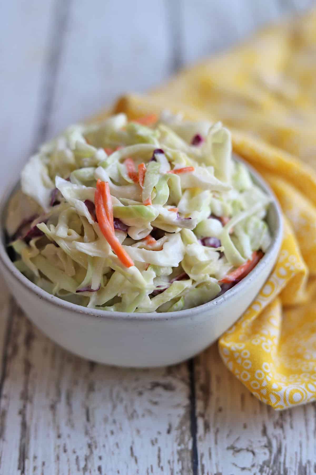 Colorful vegan coleslaw by yellow napkin.
