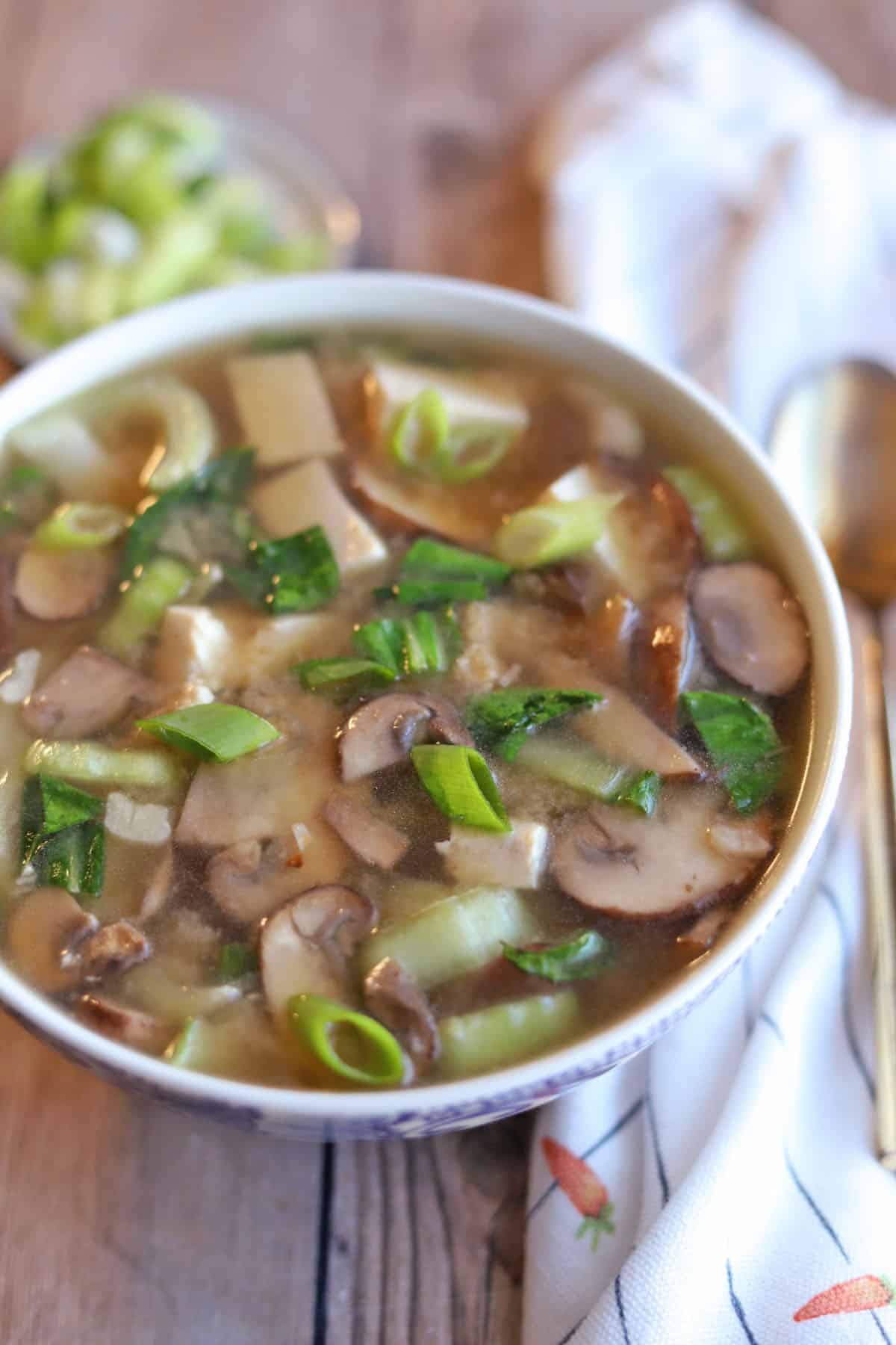 Close-up mushrooms and bok choy in miso soup.