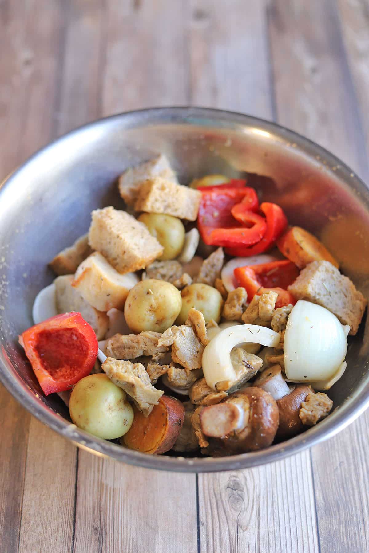 Bread, potatoes, sweet potatoes, bell peppers, onions, and mushrooms in mixing bowl.