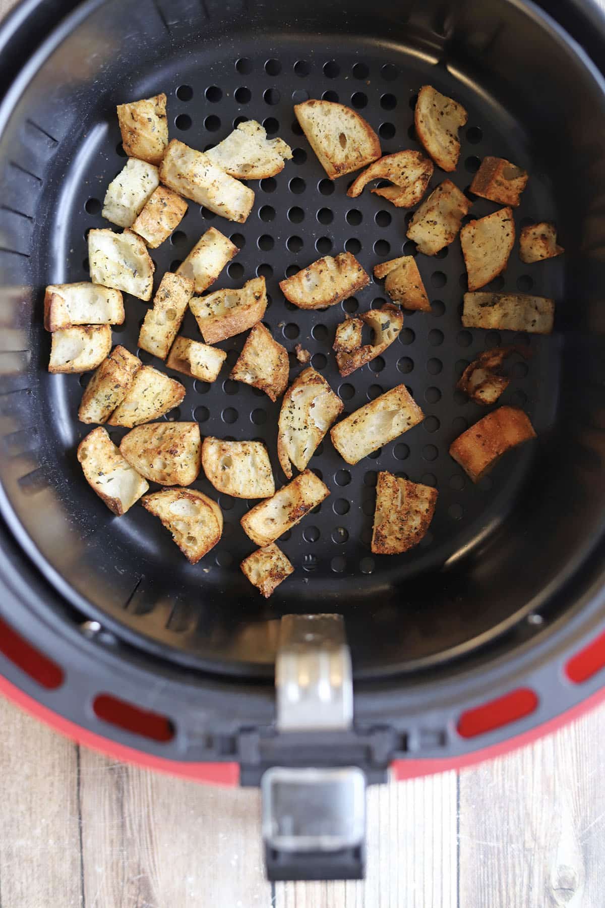 Browned croutons in air fryer basket.