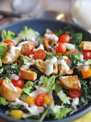 Close-up ranch dressing drizzled over homemade croutons in salad.