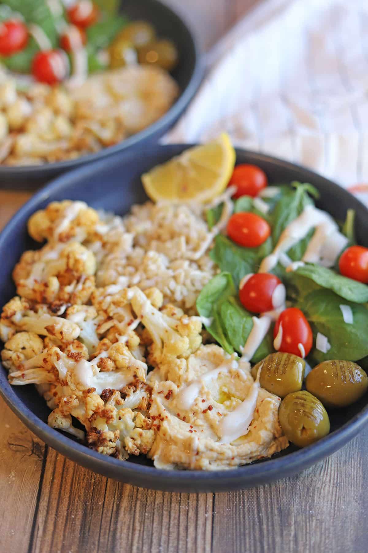 Hummus bowl with roasted cauliflower and spinach salad.