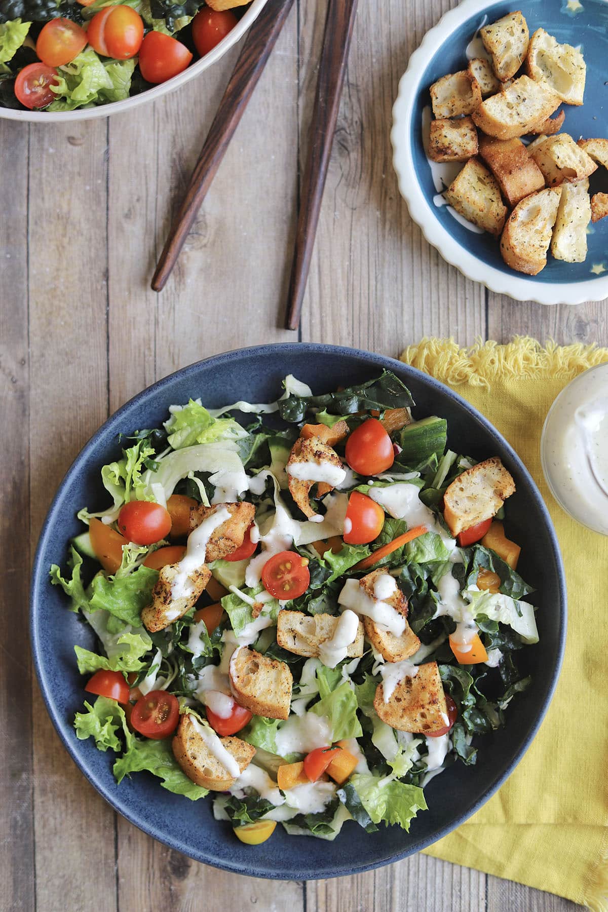 Bowl of salad topped in croutons and ranch dressing.
