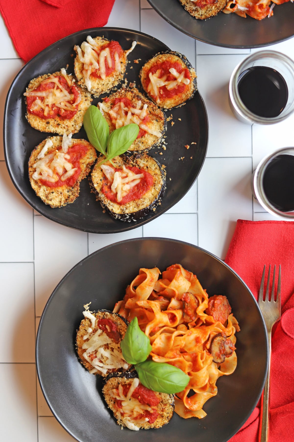 Breaded eggplant slices by bowl of pasta with basil garnish.