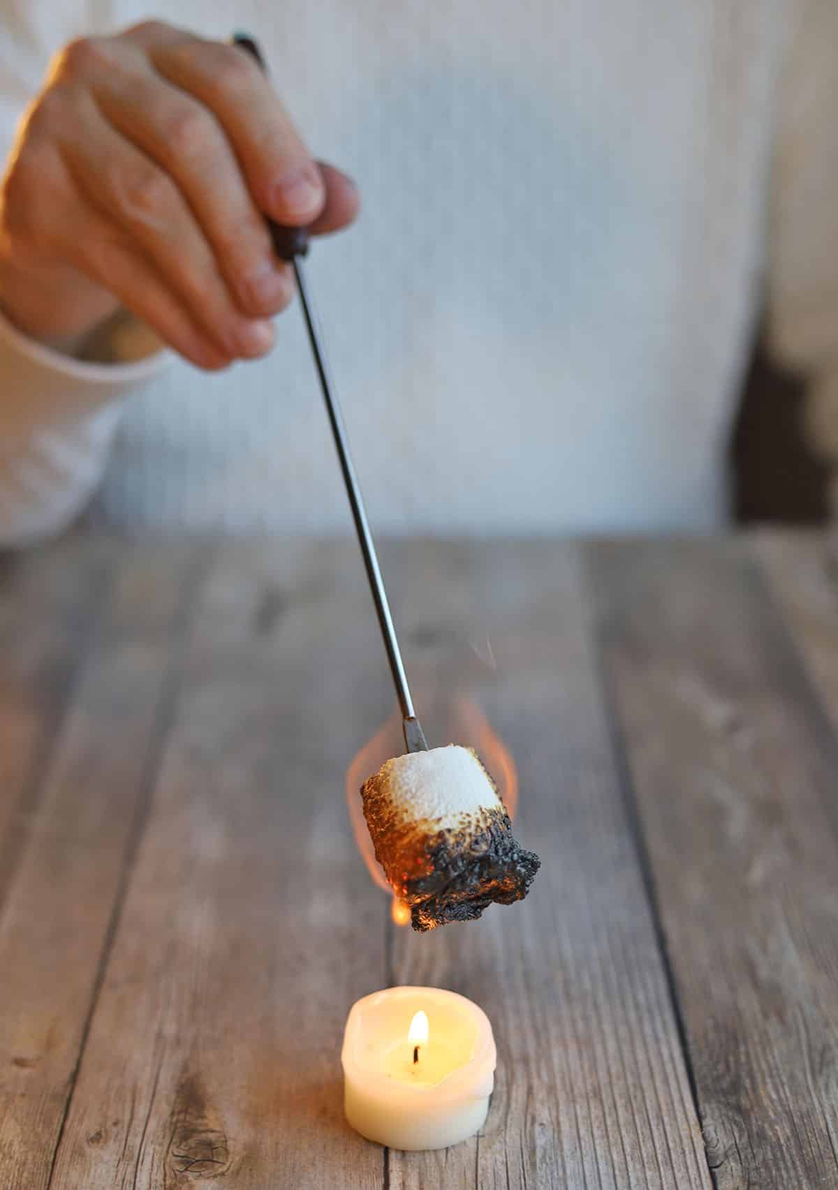 Marshmallow being roasted over candle.