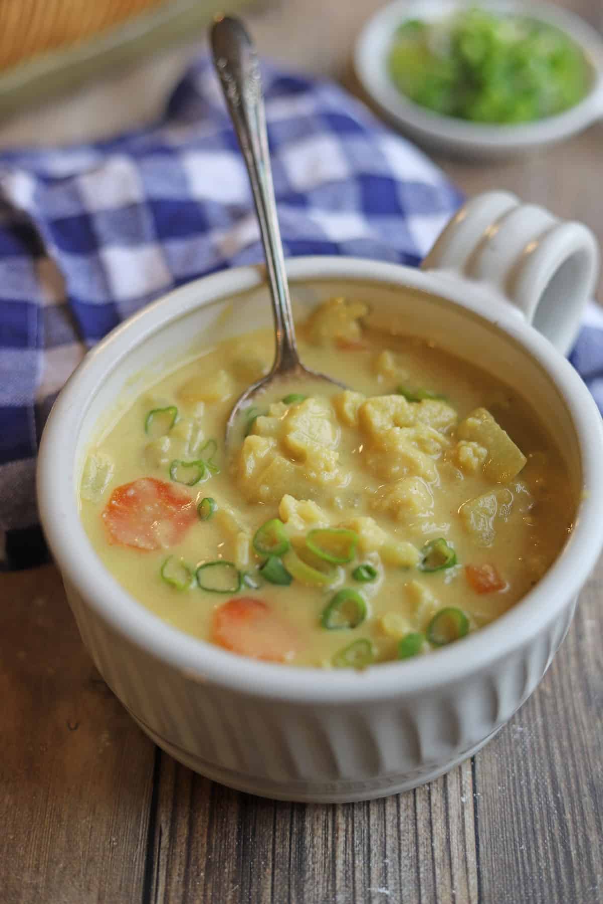Bowl of cauliflower cheese soup with scallion garnish.
