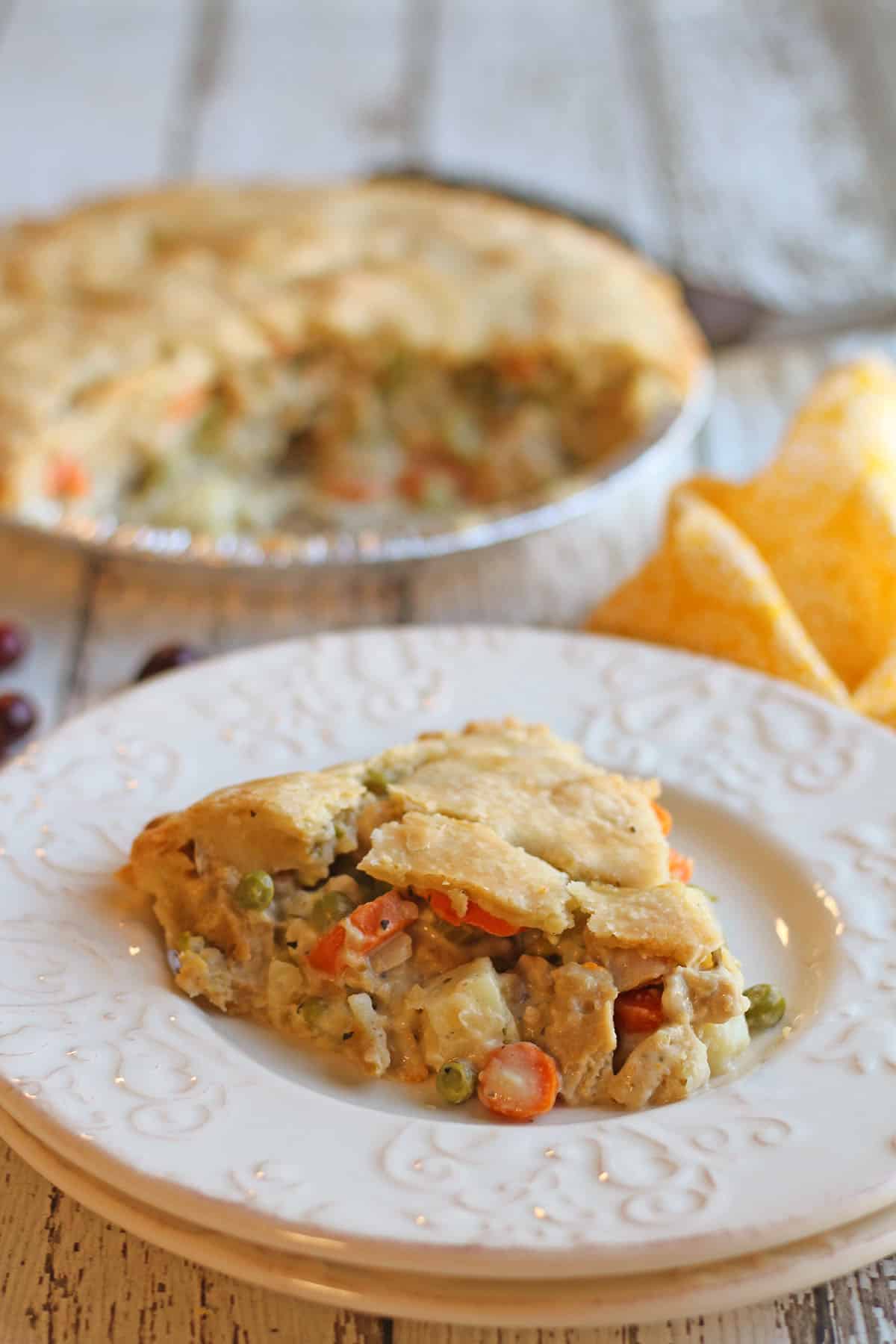 Slice of vegan chicken pot pie on table with whole pie.