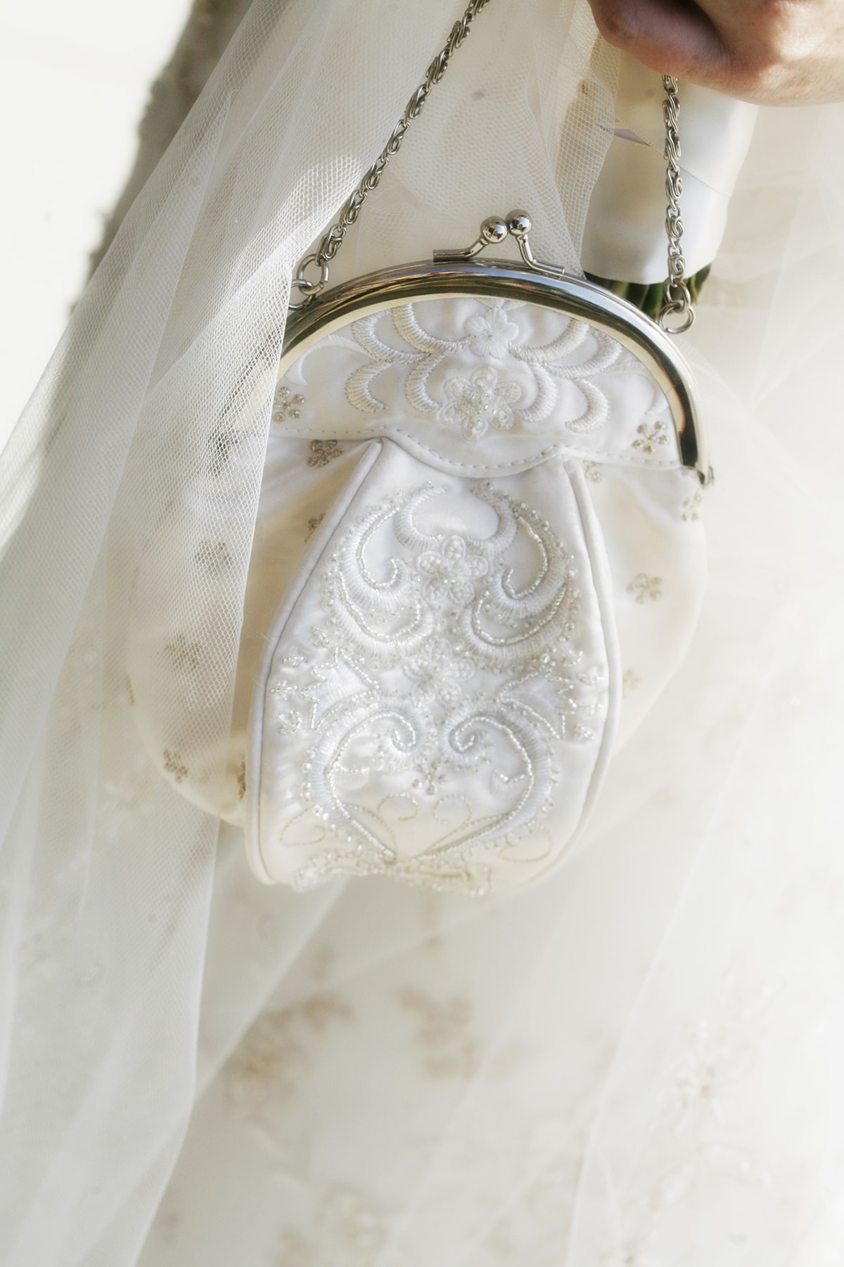 Close-up white bridal purse by gauzy fabric.