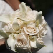 Close-up of bridal bouquet with white roses and calla lilies in hands.