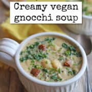 Text overlay: cadryskitchen.com, Creamy vegan gnocchi soup. Bowl of soup with vegan sausage, kale, and dumplings in cashew broth.
