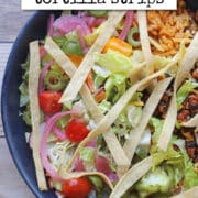 Text overlay: cadryskitchen.com, crispy air fryer tortilla strips. Crunchy corn tortilla strips on bowl with soyrizo, beans, rice, and salad.