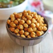Crispy air fried chickpeas seasoned with nutritional yeast and salt in striped bowl.