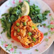 Vegan air fried stuffed peppers on plate with kale and lemon.