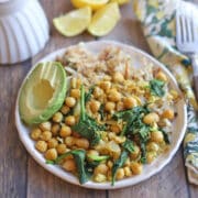 Chickpea scramble with wilted spinach, avocado, and hash browns on plate.