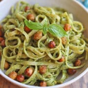 Pasta tossed with cilantro basil pistachio pesto, garnished with roasted chickpeas and fresh basil.