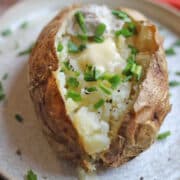 Air fryer baked potato with chives and melted non-dairy butter.