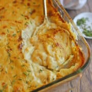 Creamy, dairy-free scalloped potatoes in casserole dish with serving spoon.