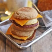 Vegan egg mcmuffin with non-dairy cheese, eggy tofu, and ham on tray.