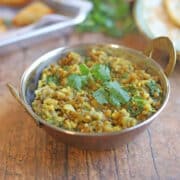 Mung bean coconut curry with kale in metal bowl.