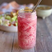 Quick pickled shallots in glass jar by salsa bowl and plate.